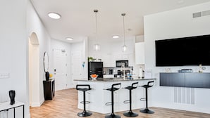 Une cuisine moderne dotée d’un îlot central, de tabourets de bar et de luminaires suspendus.