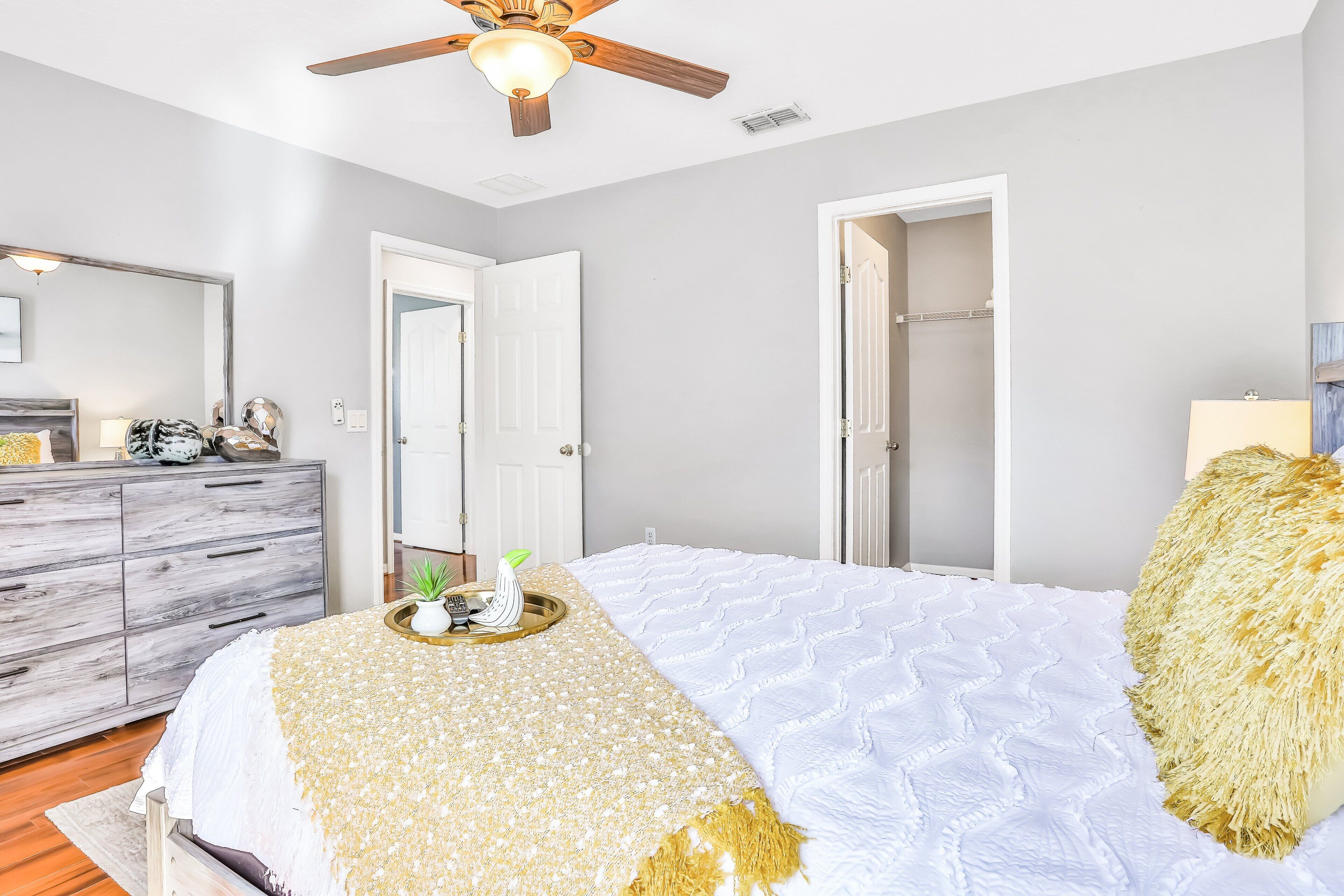 Un dormitorio con cama, ventilador de techo, cómoda y armario.
