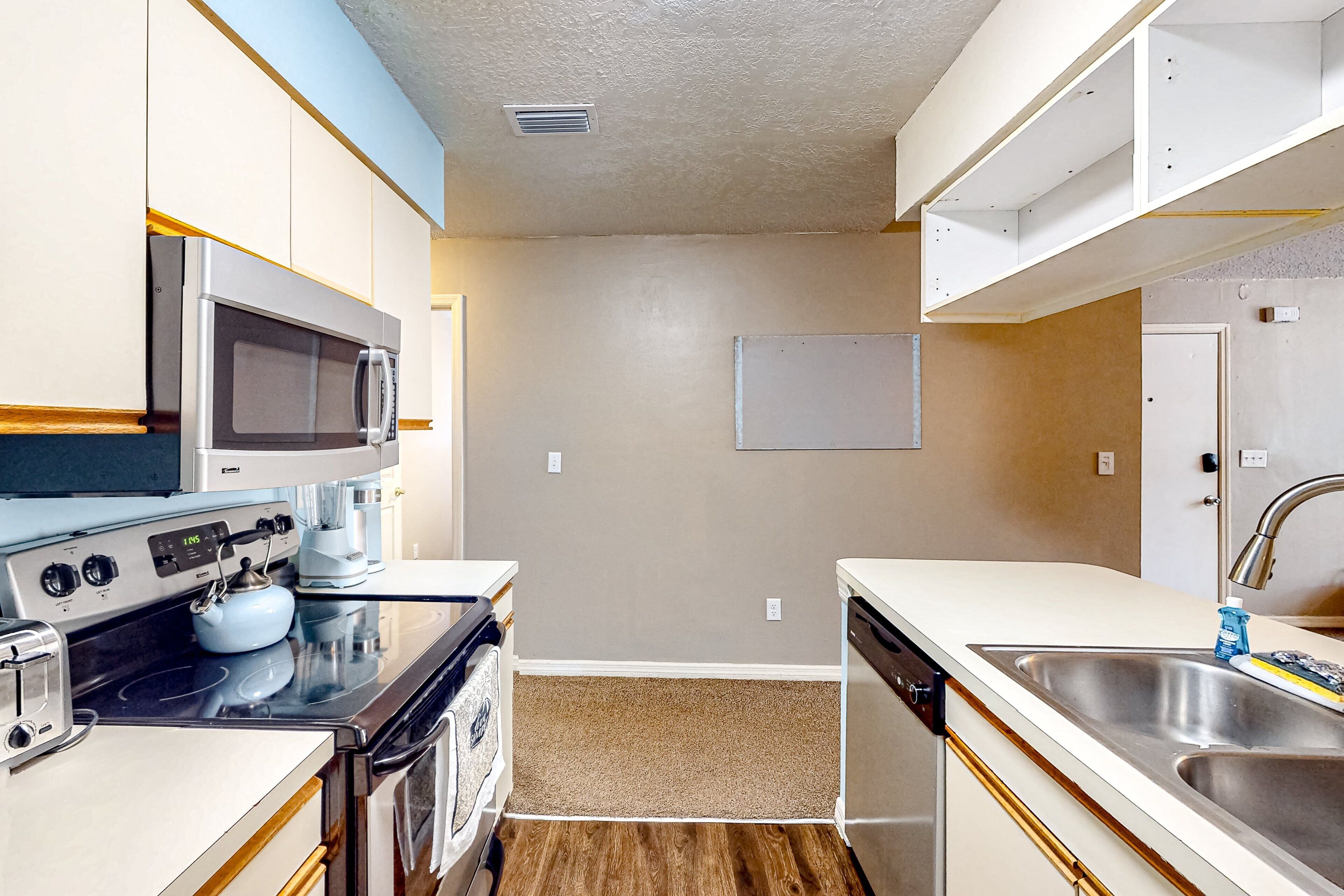 A compact kitchen with a microwave, stove, toaster, and sink.