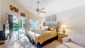 Quarto com cama, mesas de cabeceira, ventilador de teto e vista para o exterior.