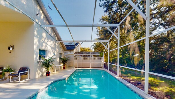 Piscina com cerca branca, plantas em vasos e um banco.