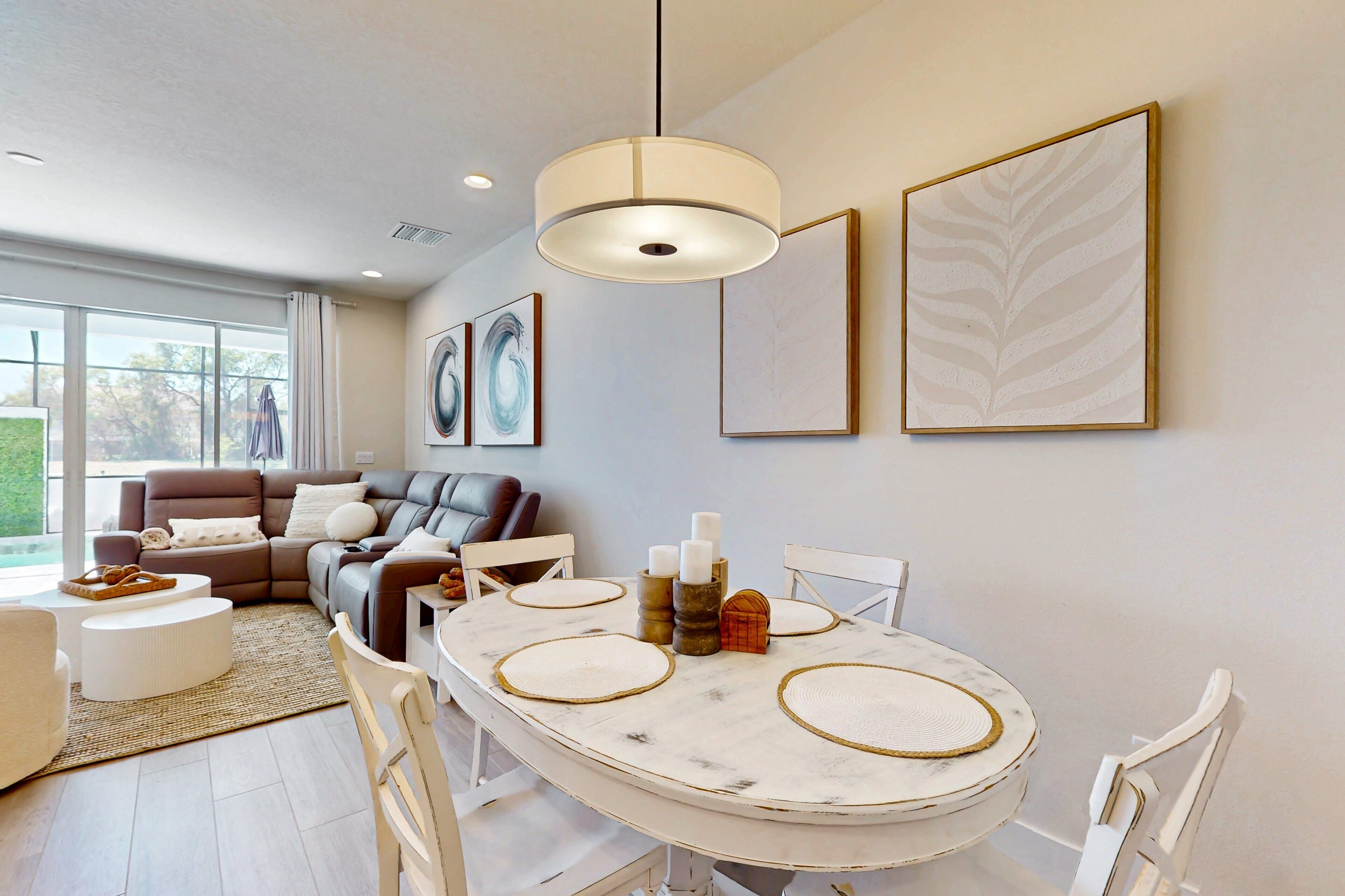 Una sala de estar moderna con una mesa de comedor blanca, sofá de cuero y ventanas grandes.