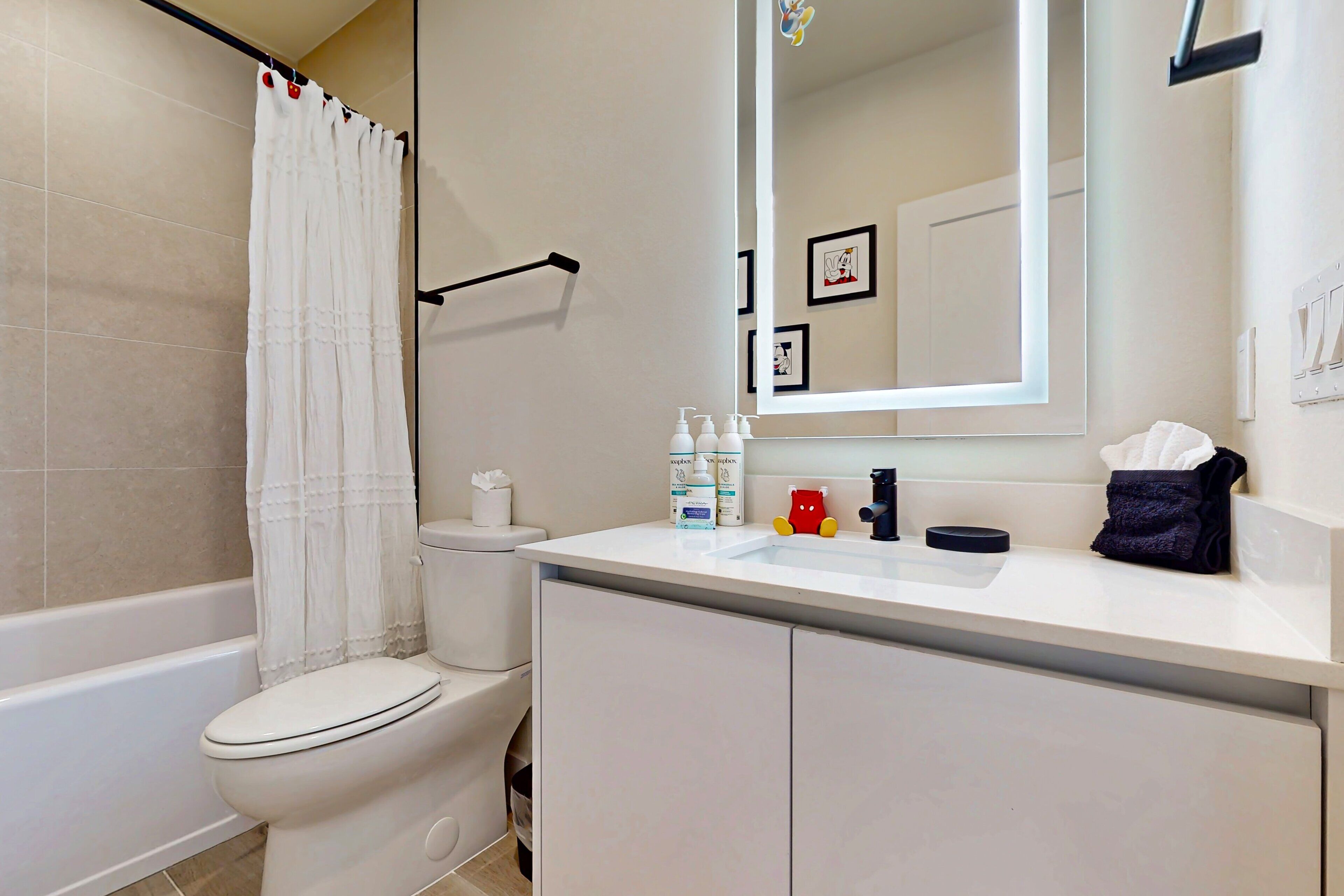 A bathroom with a toilet, a bathtub, a sink, and a mirror.
