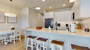 A modern kitchen with a central island, white cabinetry, and bar stools. - Beautiful Home With Private Pool and Space for the Whole Family (Clermont)