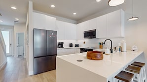 A modern kitchen with a central island, stainless steel appliances, and white cabinetry. - Beautiful Home With Private Pool and Space for the Whole Family (Clermont)