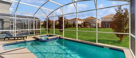 Une piscine dotée d’une structure en verre, un jacuzzi et un espace patio avec des chaises longues.