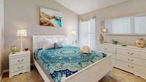 Ein Schlafzimmer mit Bett, Nachttischen, einem Schminktisch, einem Deckenventilator und einem Fenster mit Vorhängen.