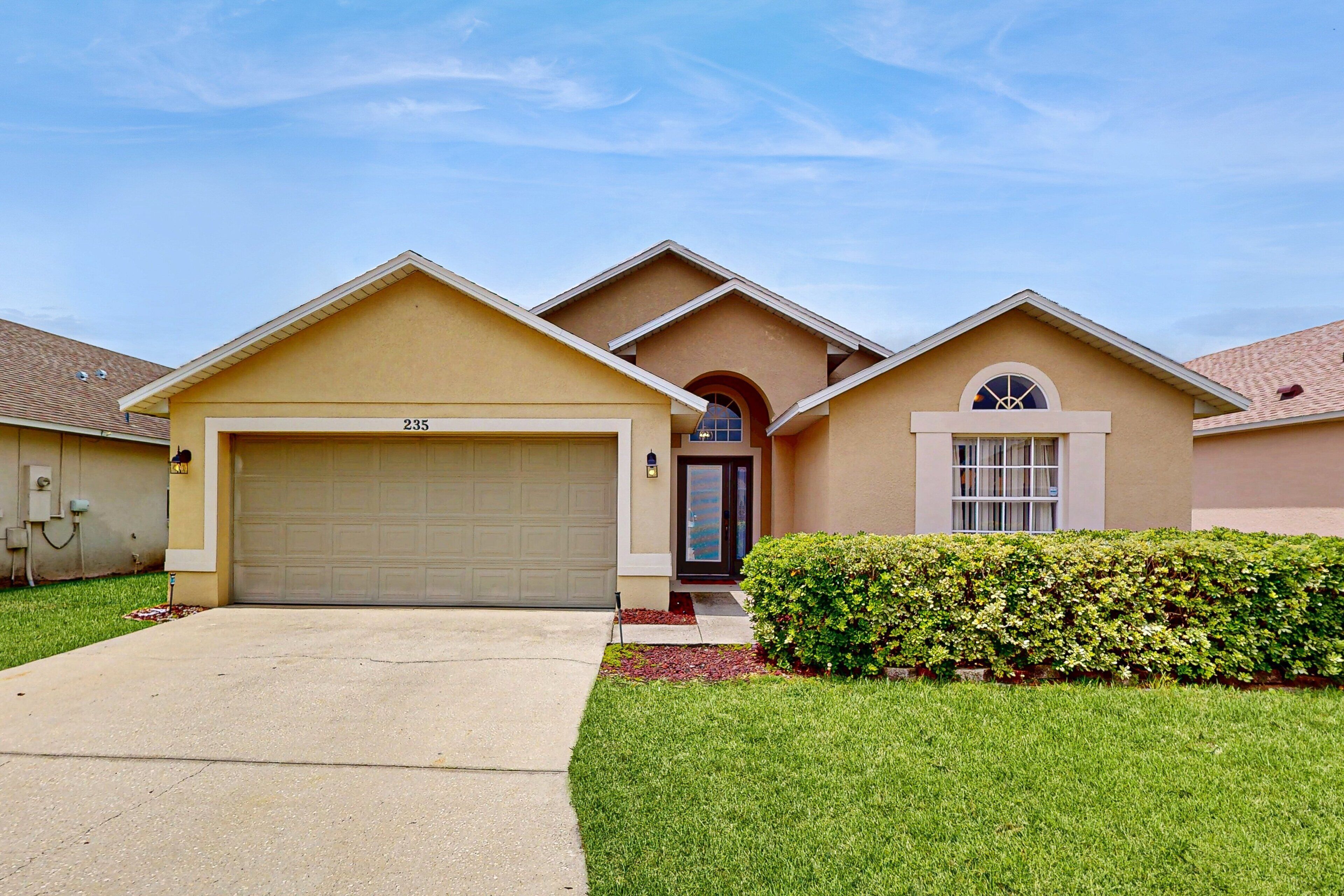A residential house with a garage, a well-maintained lawn, and a clear sky.