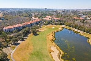 An aerial view of a residential area with apartment buildings, a golf course, and a body of water. - Resort Condo With Heated Pool, Gym, BBQ Area, Balcony, W/d, Children's Pool, AC (Davenport)