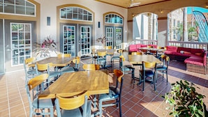 A spacious indoor dining area with multiple tables and chairs, large windows, and a seating area with a red sofa. - Resort Condo With Heated Pool, Gym, BBQ Area, Balcony, W/d, Children's Pool, AC (Davenport)