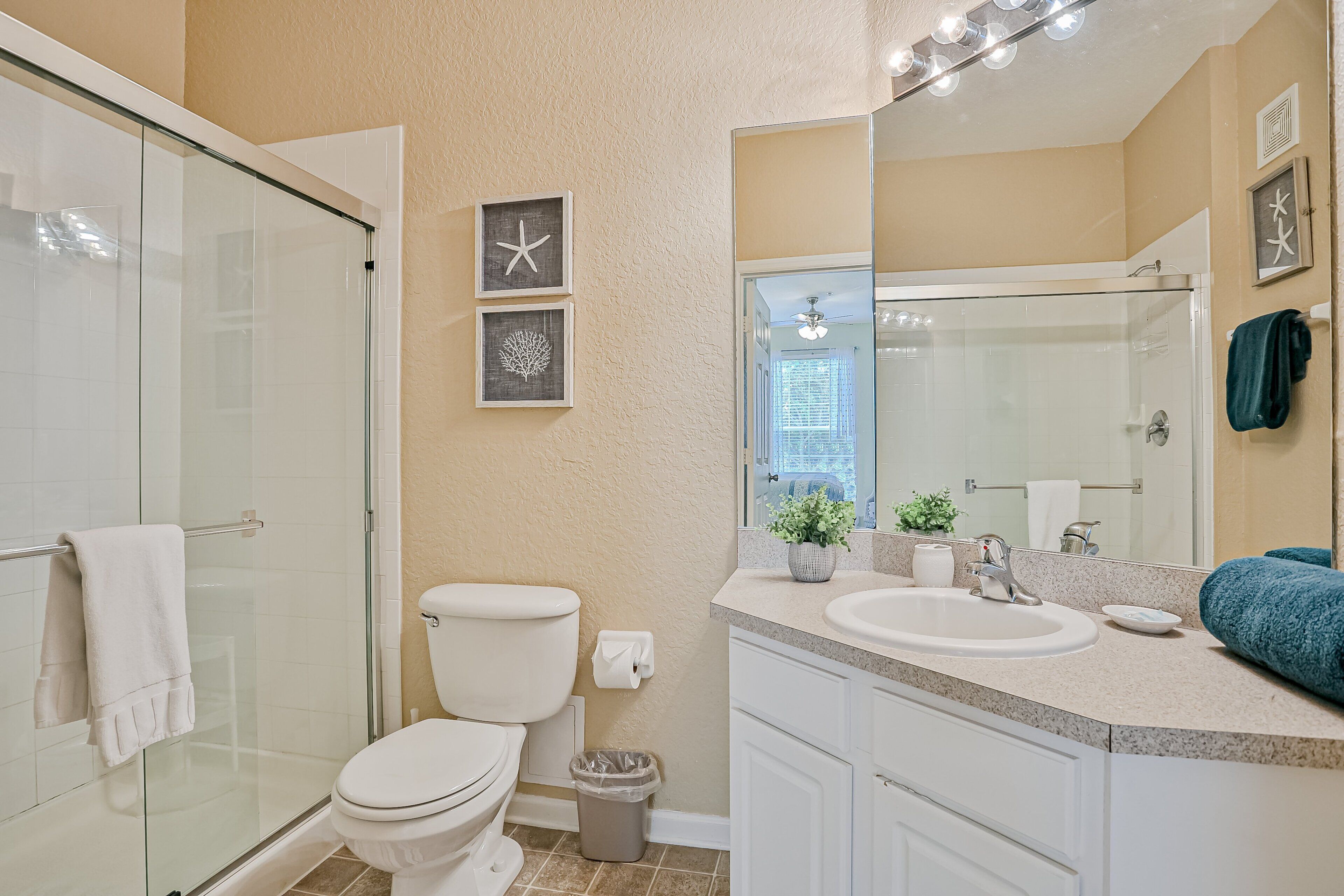 A bathroom with a glass shower enclosure, a toilet, a sink with a mirror, and a towel rack.