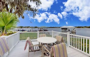 A deck with a table and chairs, overlooking a lake with boats and a gazebo. - Spacious Lakefront House With Private Dock , gas Grill, Deck and Patio (Lake Placid)