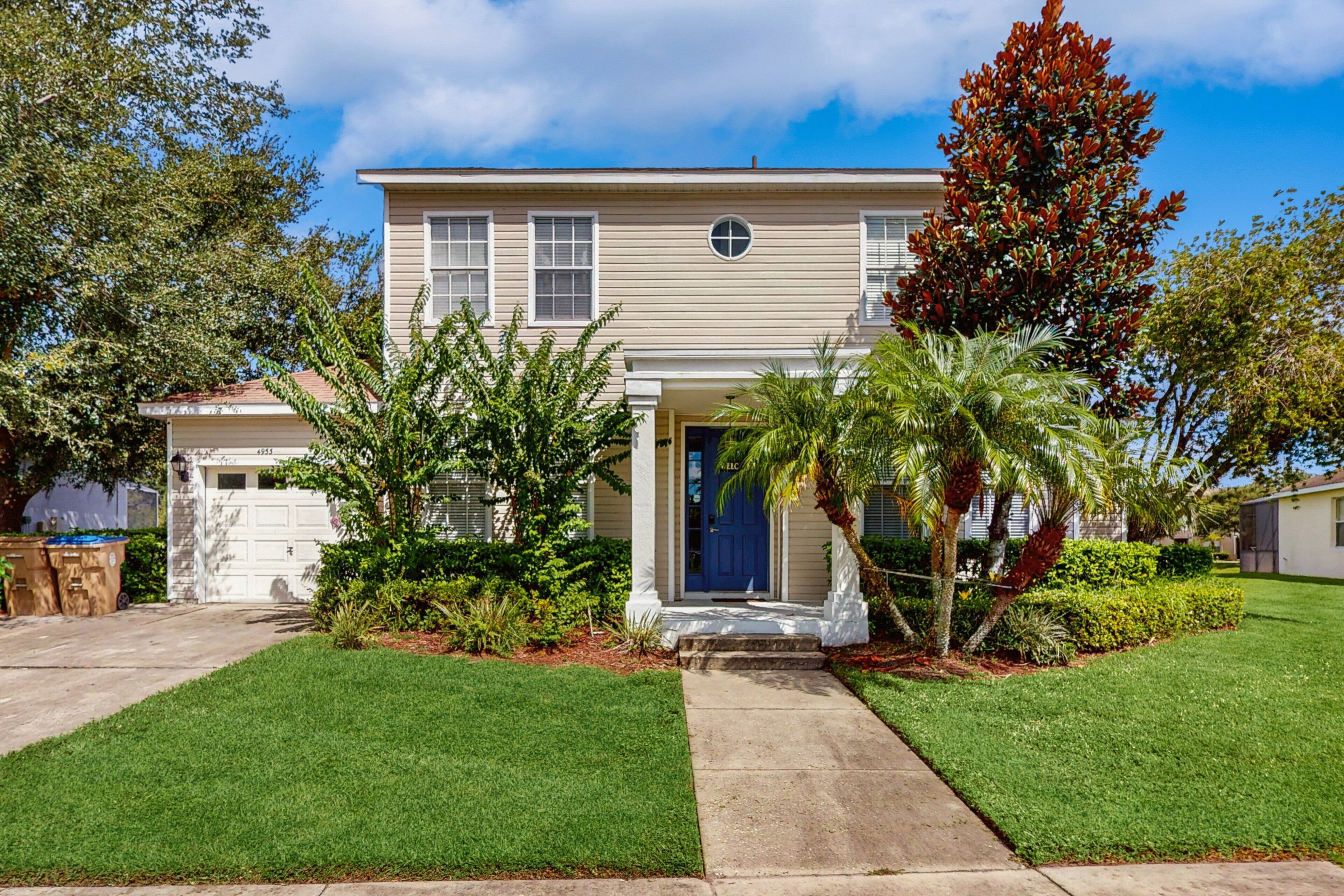A two-story house with a front porch, a garage, and a well-maintained lawn.