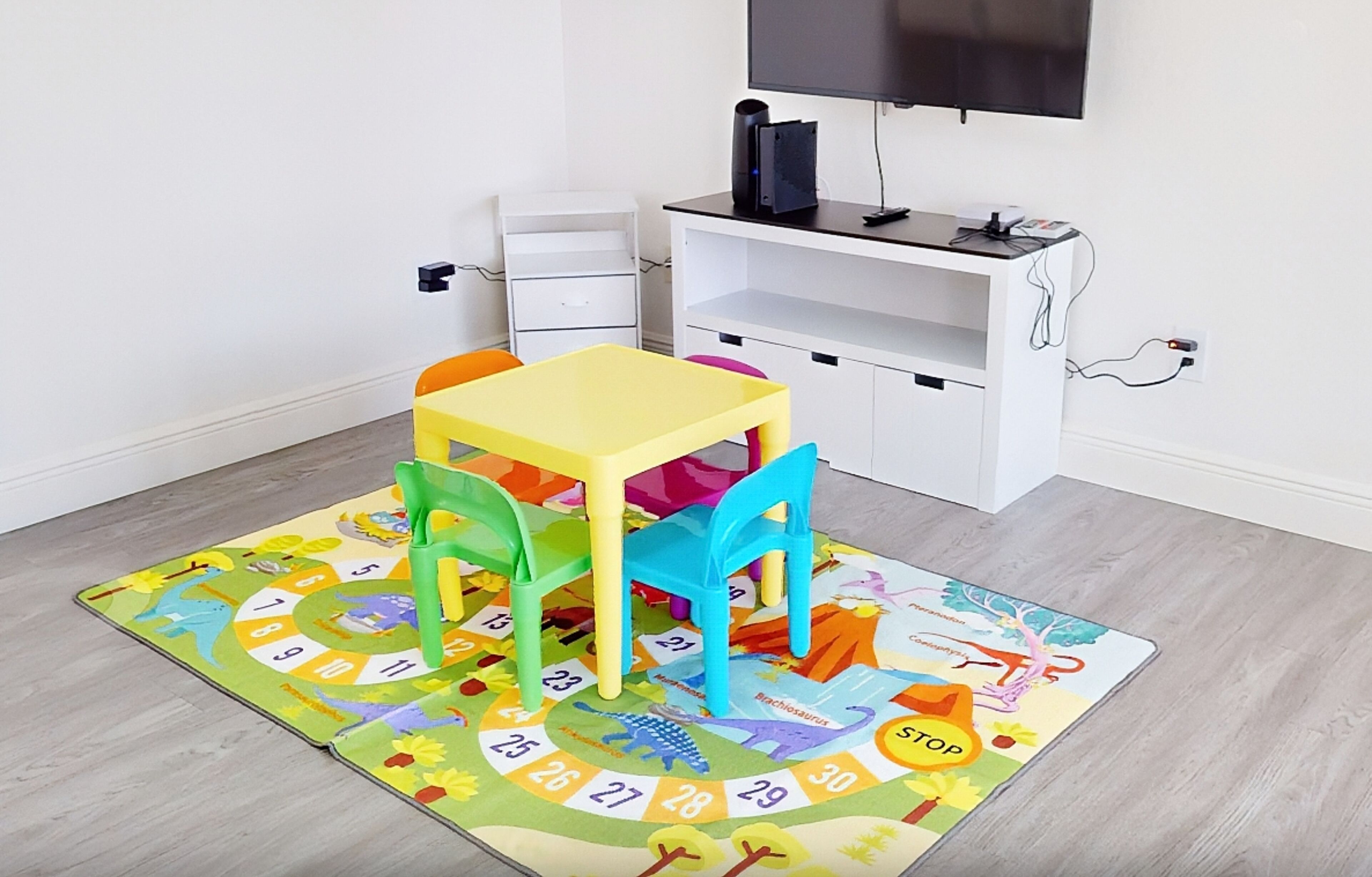 A child's play area with a colorful mat, chairs, and a small table.