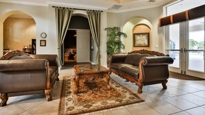 A spacious lobby with a grand staircase, leather sofas, a coffee table, and a large window. - Water View Retreat With Lanai, Heated Pool, Pool Spa, Game Room, & AC (Kissimmee)