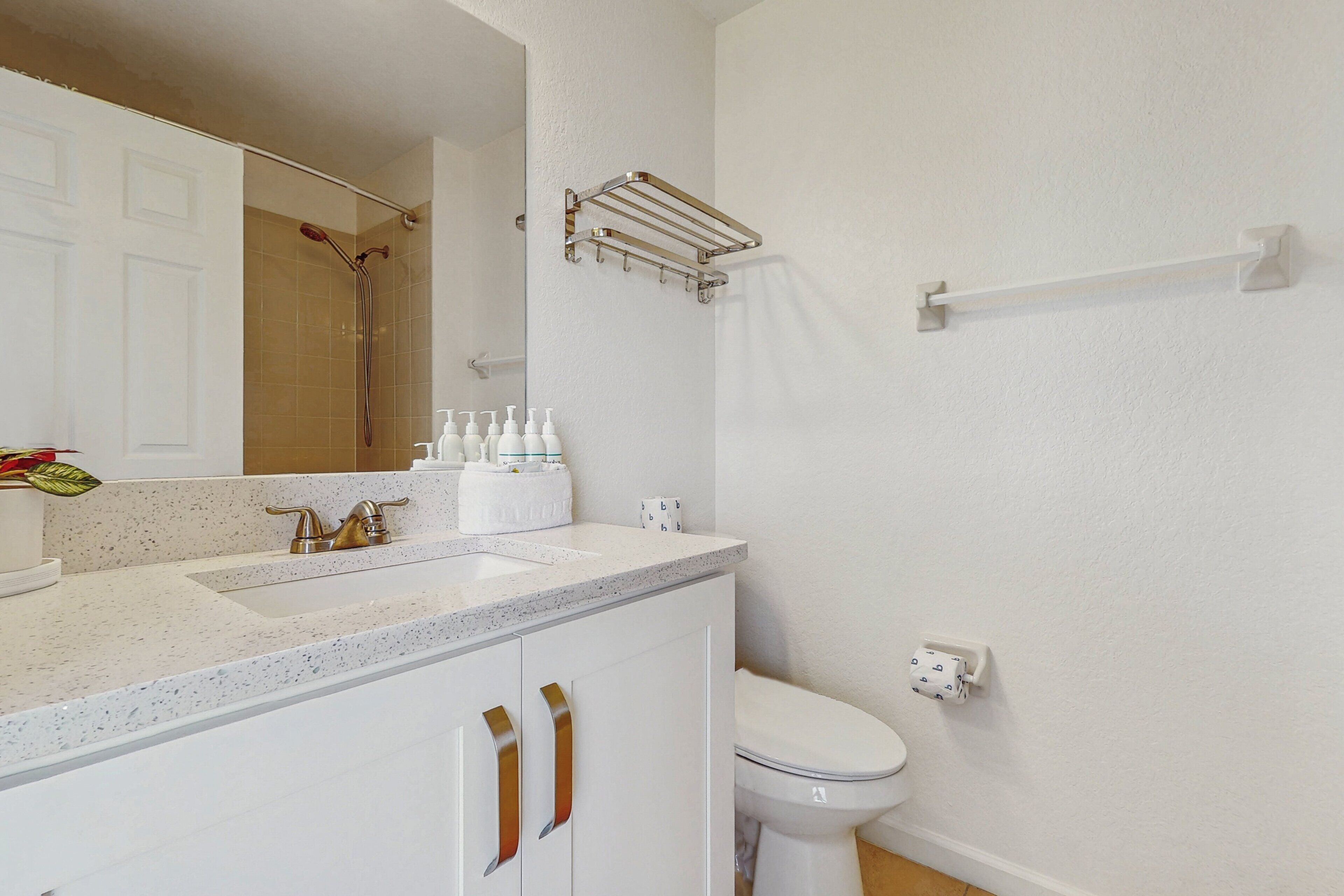 A bathroom with a sink, mirror, toilet, and towel rack.
