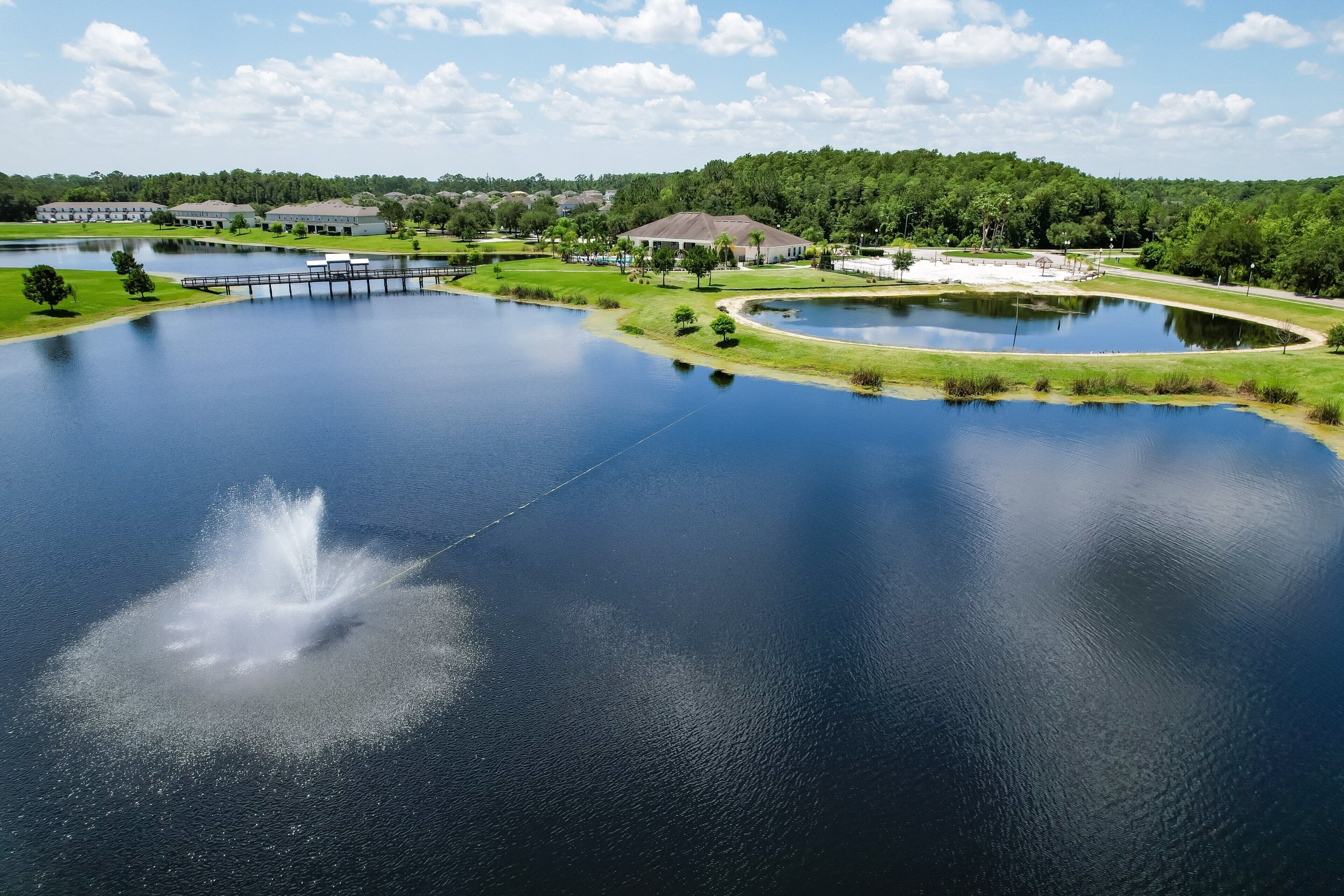 A large body of water with a fountain, surrounded by greenery and buildings.