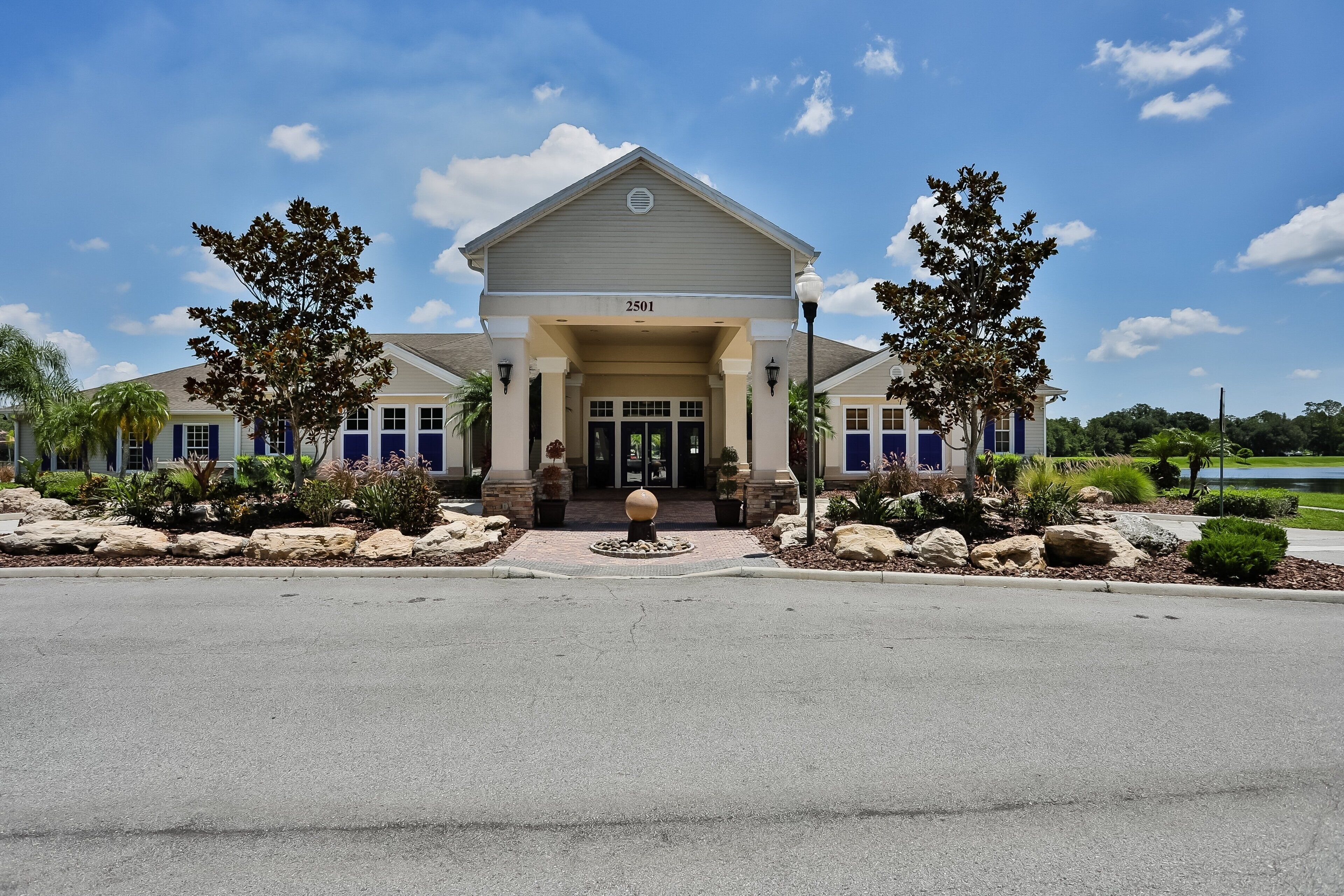 A building with a number '2501' on the front, a covered entrance, and a landscaped area with rocks and trees.