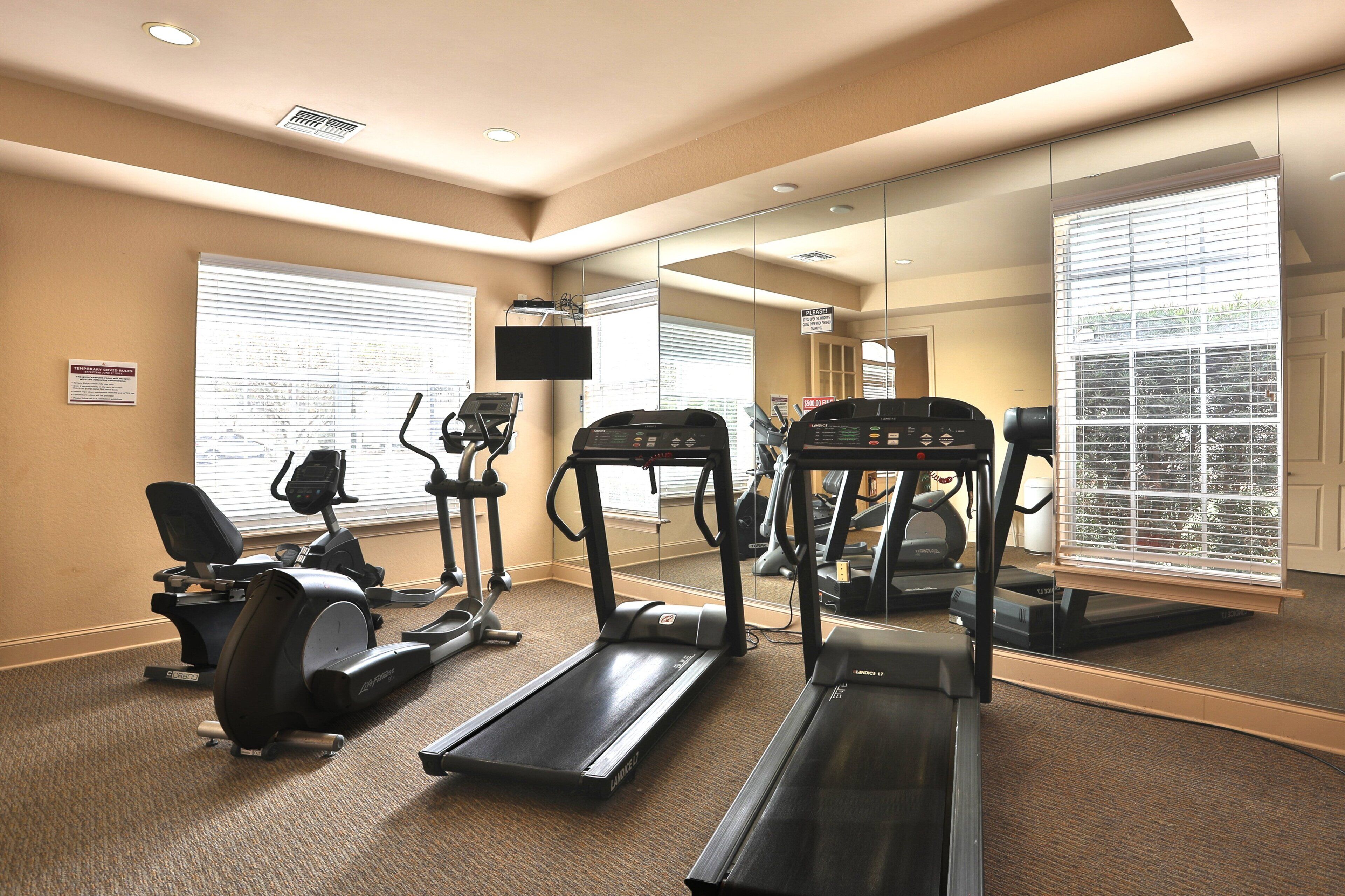 Une salle de sport équipée de tapis de course, d’un vélo elliptique et d’un vélo d’appartement.