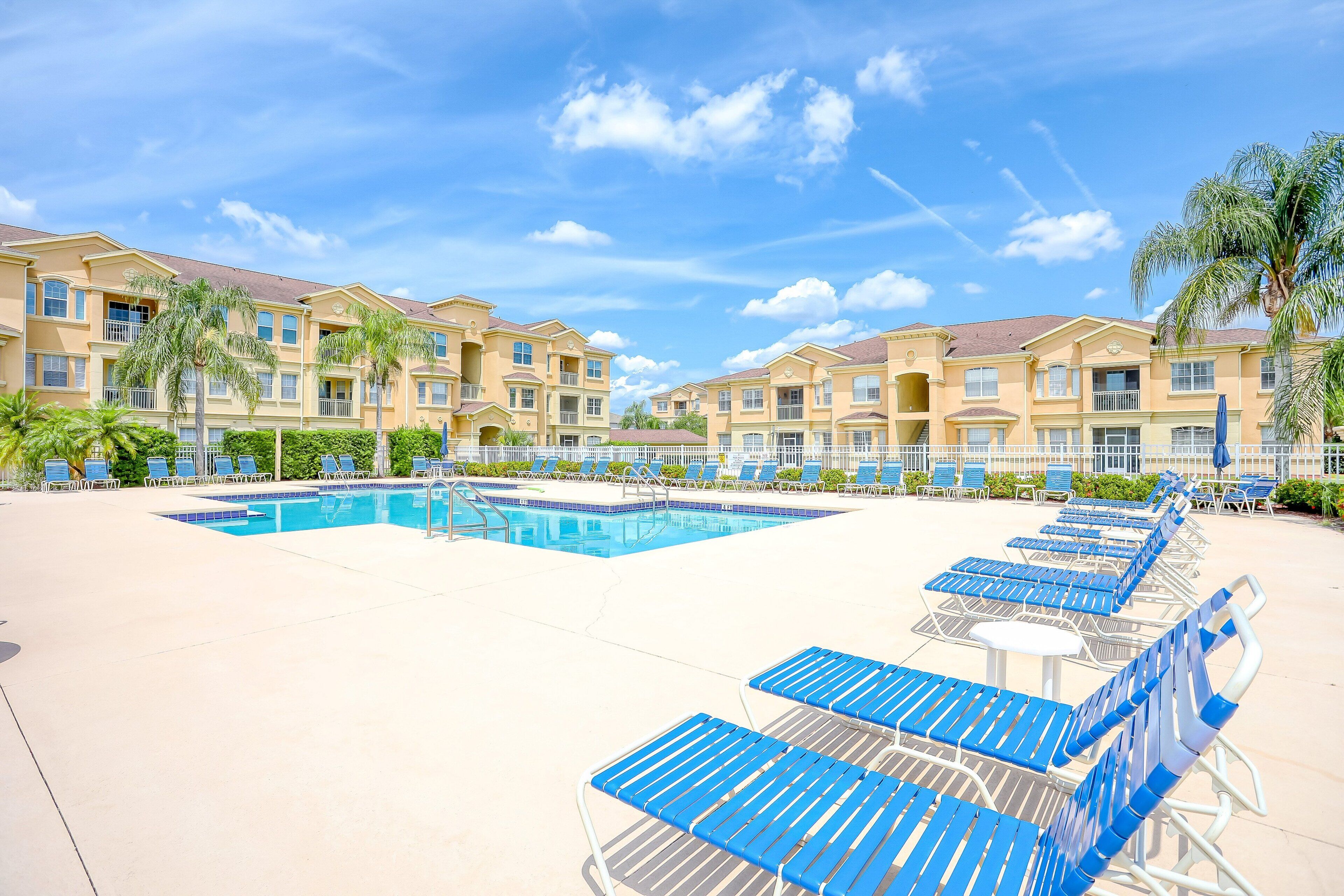 Et hotel med swimmingpool, liggestole og palmer.