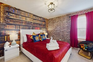 A bedroom with a brick wall, a bookshelf, a bed with red bedding, a nightstand, and a chair. - Dog-friendly House With Private Heated Pool, Sports Courts, Game Room, Pool, AC (Davenport)
