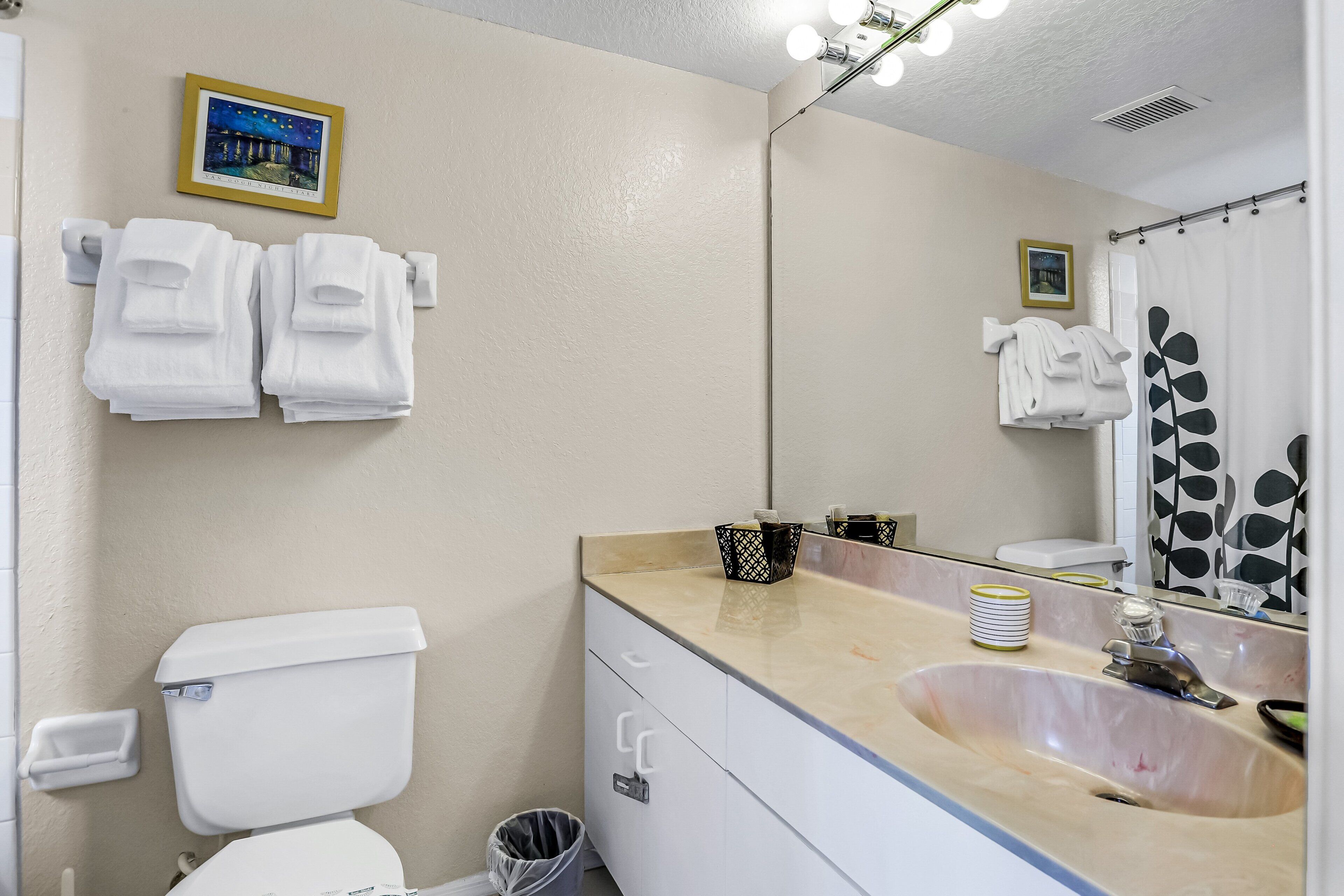 A bathroom with a toilet, sink, towels, and a mirror.