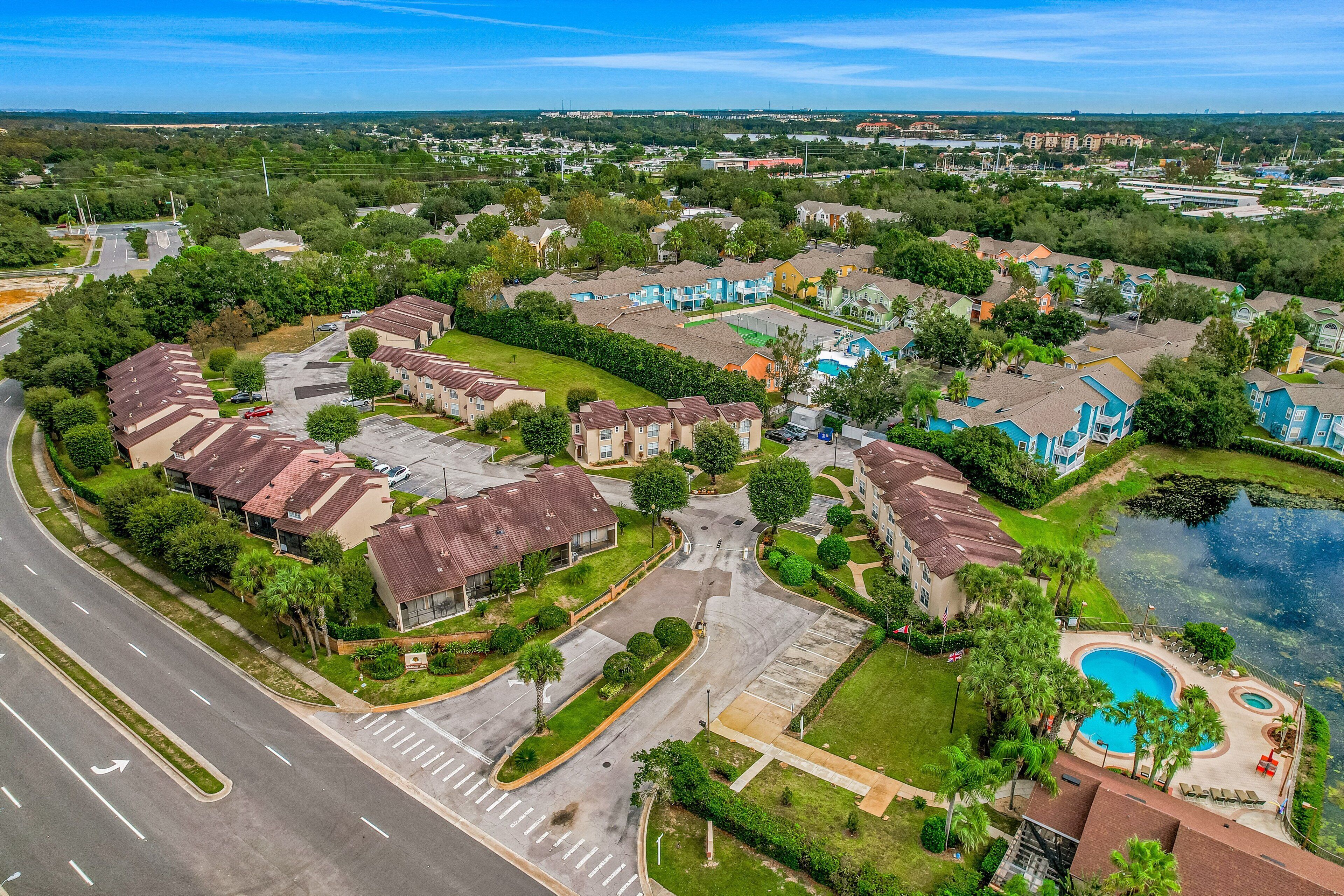 Vue aérienne d’un quartier résidentiel avec des maisons, une piscine et une route.