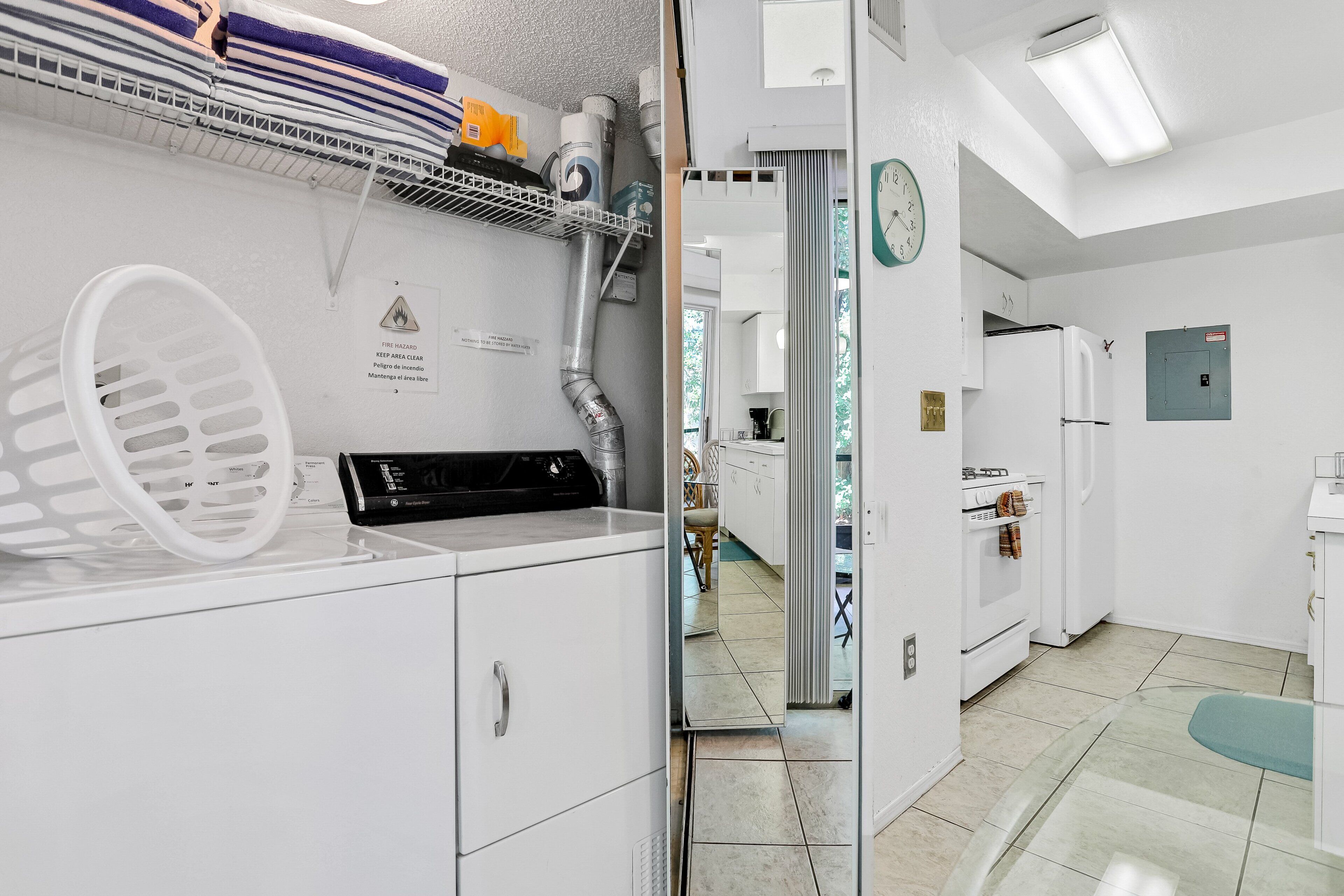 A laundry area with a dryer, a vent, and a caution sign.
