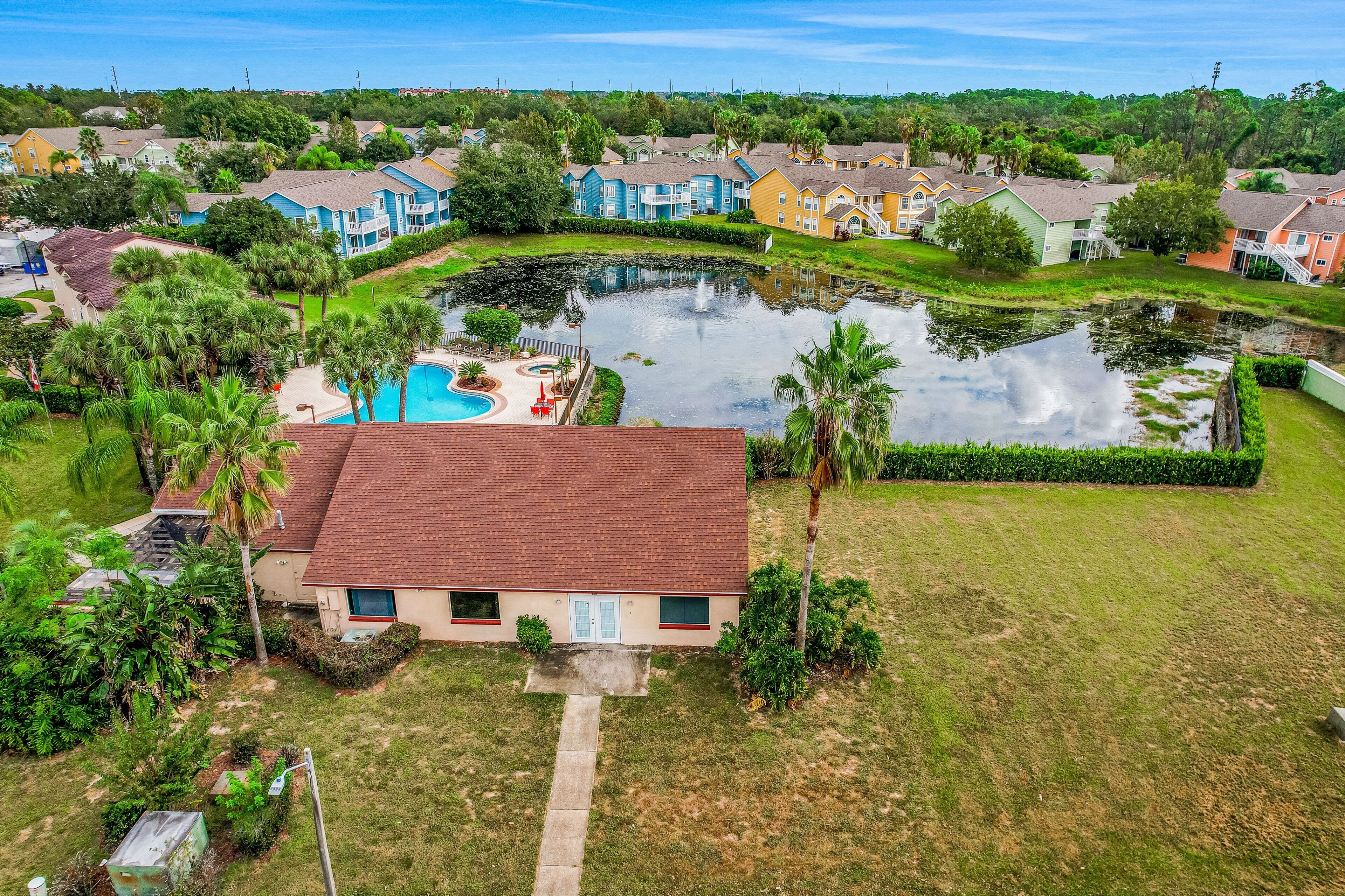 A residential area with a swimming pool, a pond, and houses with various roof colors.