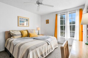 A bedroom with a bed, a ceiling fan, a window with curtains, and a framed picture on the wall. - Breezy Townhouse With a Pool, hot Tub, Patio, Central AC, and Washer/dryer (Kissimmee)