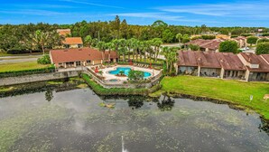 A residential area with a swimming pool, houses, and a body of water. - Breezy Townhouse With a Pool, hot Tub, Patio, Central AC, and Washer/dryer (Kissimmee)