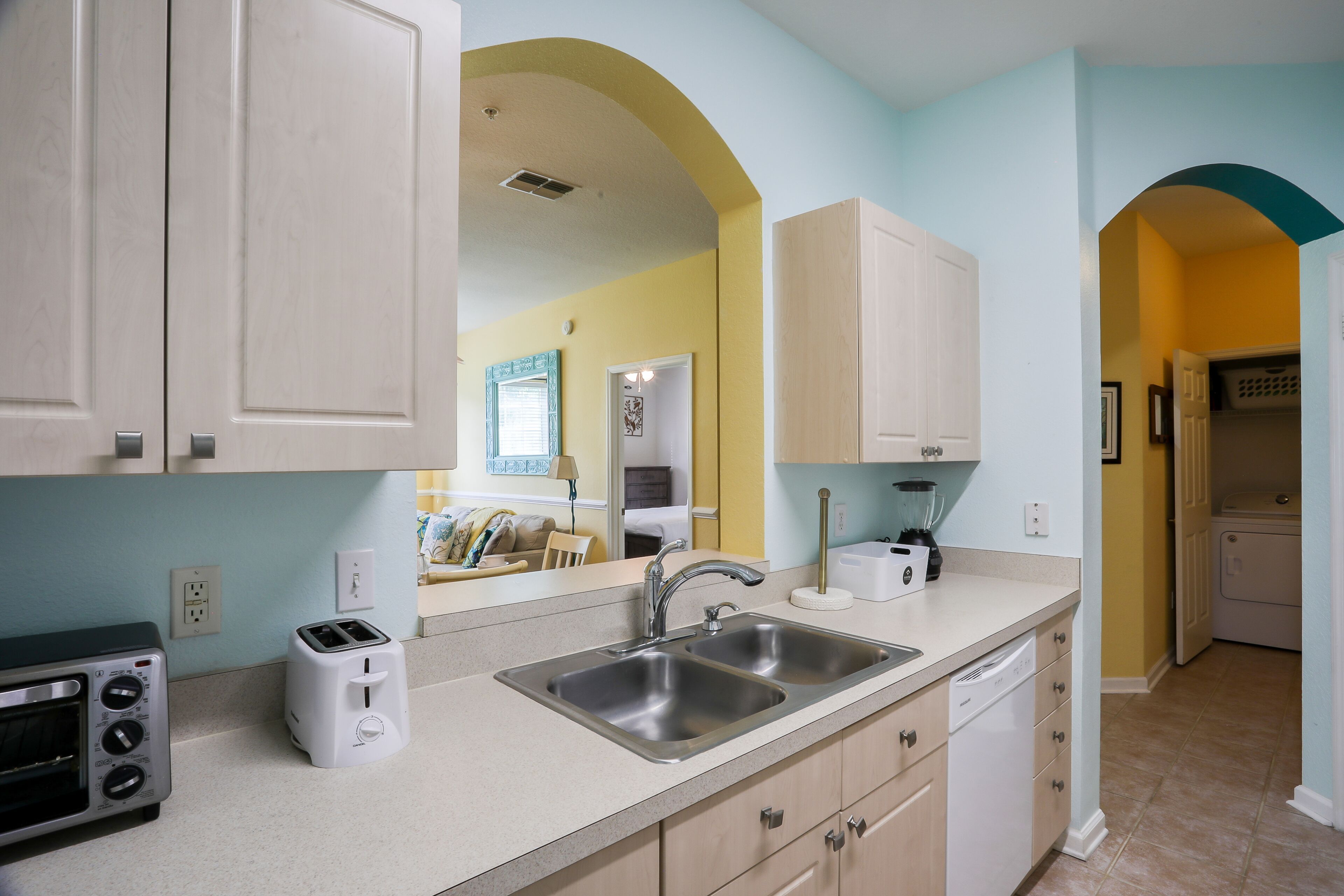 A kitchen with a double sink, a toaster, and a dishwasher.