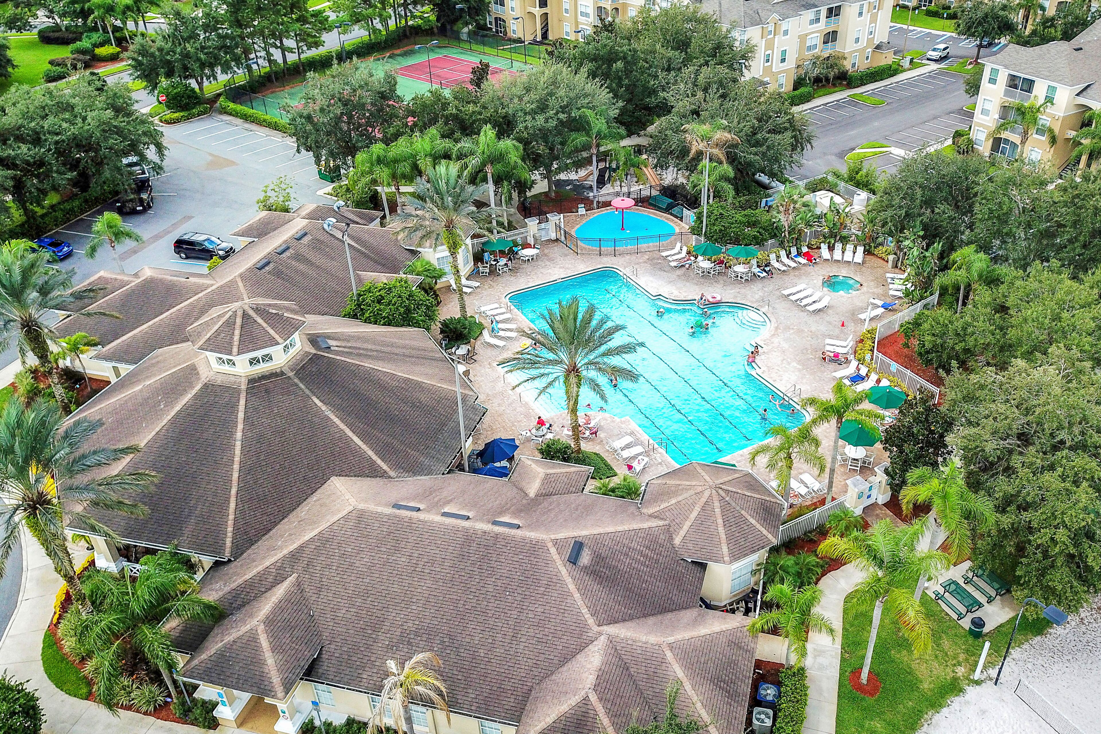A hotel with a swimming pool, lounge chairs, and palm trees.