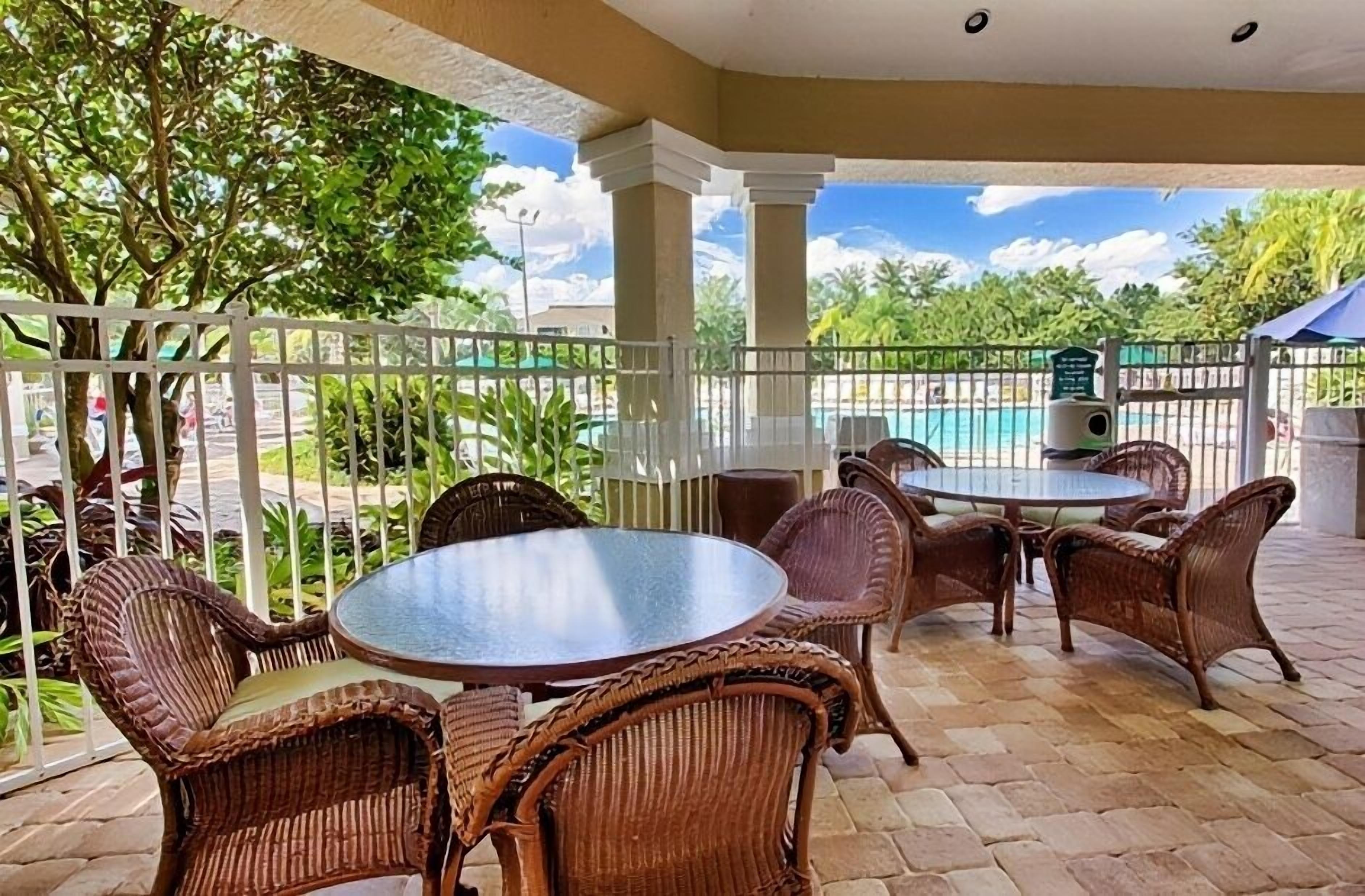 A covered outdoor seating area with wicker furniture and a view of a swimming pool.