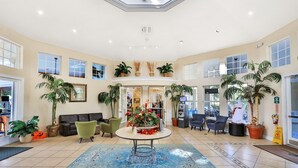 A spacious lobby with a central round table, multiple seating areas, and large windows allowing natural light. - Resort Condo Near Disney With Pool, hot Tub, Tennis, Central AC, & Washer/dryer (Kissimmee)