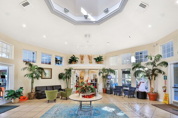 A spacious lobby with a central round table, multiple seating areas, and large windows allowing natural light. - Resort Condo Near Disney With Pool, hot Tub, Tennis, Central AC, & Washer/dryer (Kissimmee)