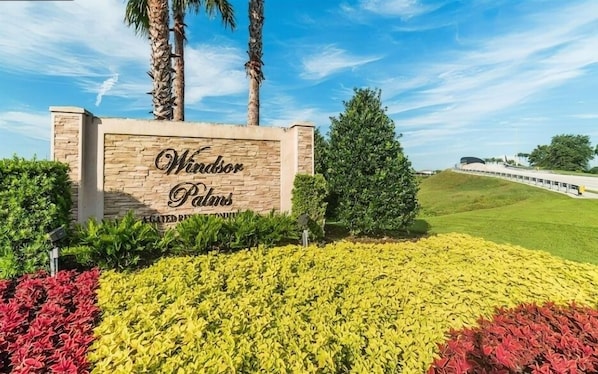 A sign for Windsor Palms with a landscaped garden in front. - Resort Condo Near Disney With Pool, hot Tub, Tennis, Central AC, & Washer/dryer (Kissimmee)