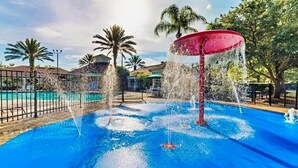 A swimming pool with a central water feature and surrounding palm trees. - Resort Condo Near Disney With Pool, hot Tub, Tennis, Central AC, & Washer/dryer (Kissimmee)