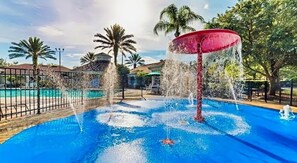 A swimming pool with a central water feature and surrounding palm trees. - Resort Condo Near Disney With Pool, hot Tub, Tennis, Central AC, & Washer/dryer (Kissimmee)