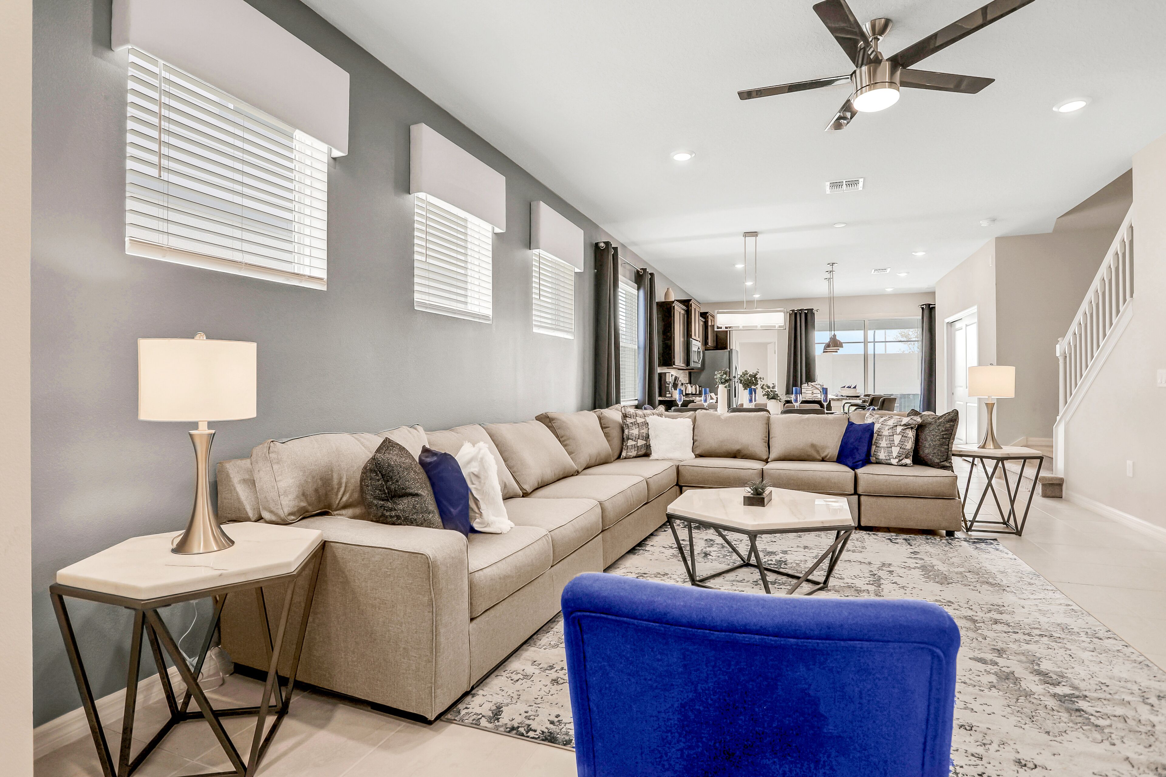 A modern living room with a sectional sofa, a blue armchair, and a coffee table.