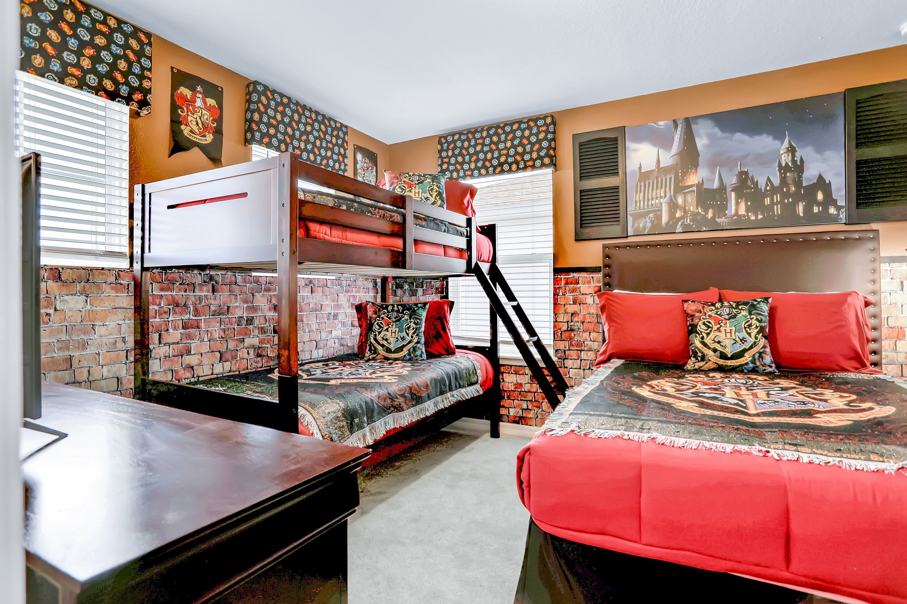 A room with a bunk bed, a desk, and a large window with blinds.