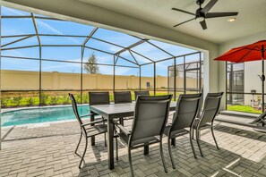 A covered patio with a pool, outdoor seating, and a ceiling fan. - Spacious Resort Home With Private Pool, Game Room, & Abundant Amenities (Davenport)
