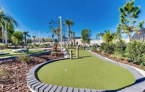 A golf course with a putting green, surrounded by landscaped areas and trees. - Spacious Resort Home With Private Pool, Game Room, & Abundant Amenities (Davenport)