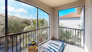 A balcony with a view of a residential area, a striped sofa, and a decorative lamp. - Calm Condo With Pool, hot Tub, Balcony, Cabana, & Kitchen - Snowbird-friendly (Davenport)