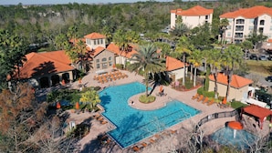 A resort with a large swimming pool, lounge areas, and multiple buildings with red-tiled roofs. - Calm Condo With Pool, hot Tub, Balcony, Cabana, & Kitchen - Snowbird-friendly (Davenport)