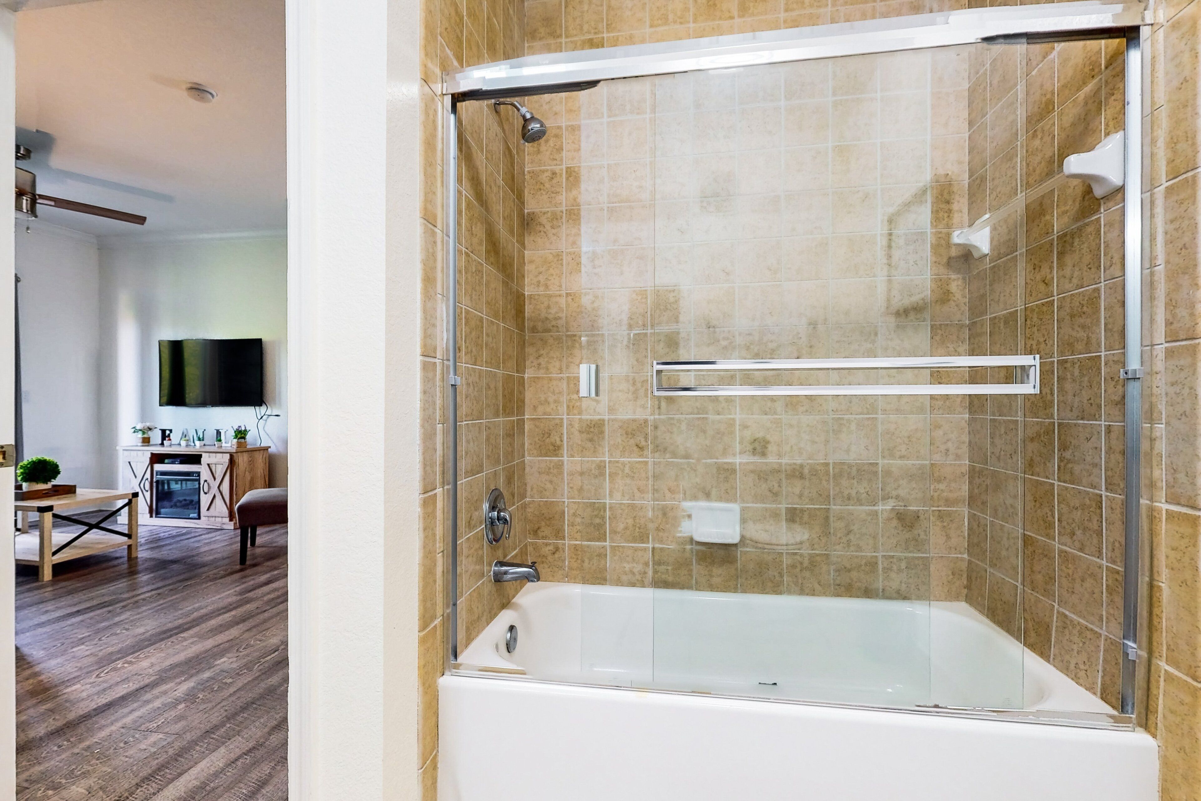 Un baño moderno con ducha de vidrio, bañera y piso de baldosas.