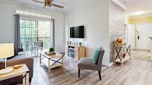 A spacious living room with a ceiling fan, a flat-screen TV, a wooden cabinet, and a dining area with a table and chairs. - Tuscan Lane (Davenport)