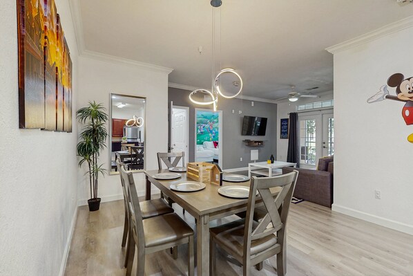 A dining area with a wooden table and chairs, a potted plant, and a painting on the wall. - Tuscan Lane (Davenport)