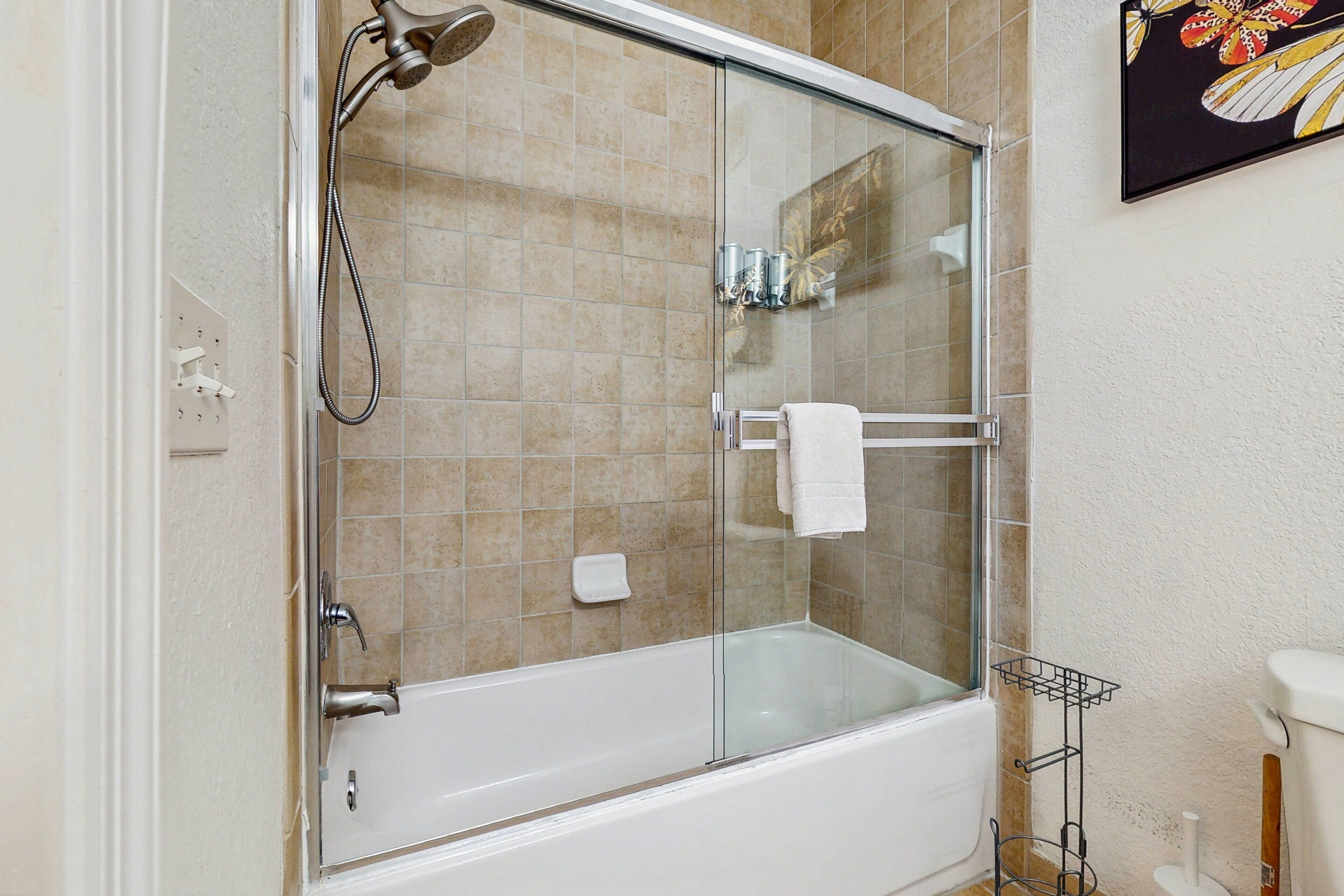 A modern bathroom with a glass-enclosed shower, a white bathtub, and a toilet.