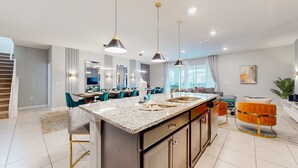 A modern kitchen with granite countertops, a central island, and pendant lighting. - Inviting Family-friendly Home W/private Pool, Spa, Central AC, & W/D (Davenport)
